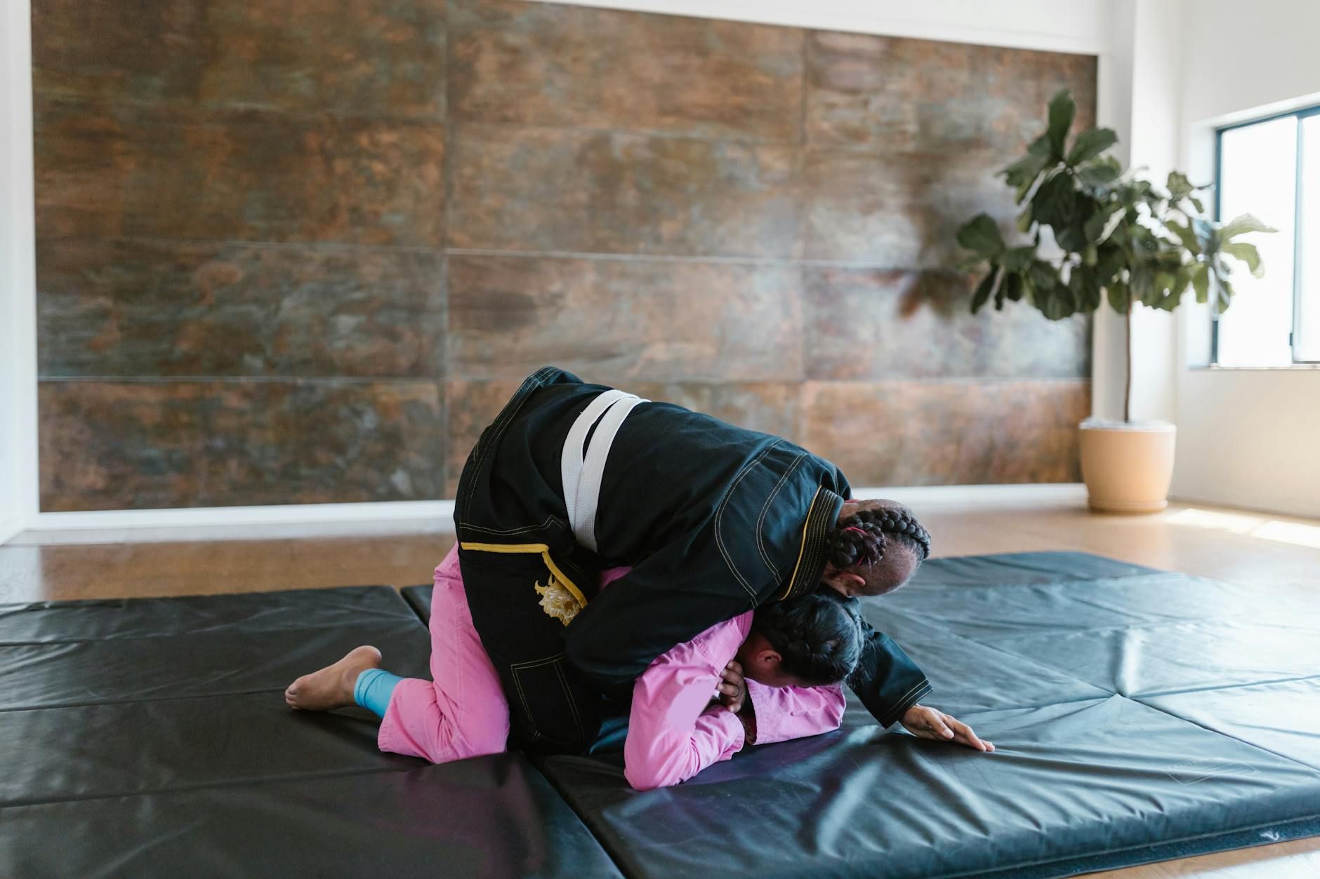 Two martial artists practicing grappling techniques indoors on a mat, emphasizing sportsmanship and training.